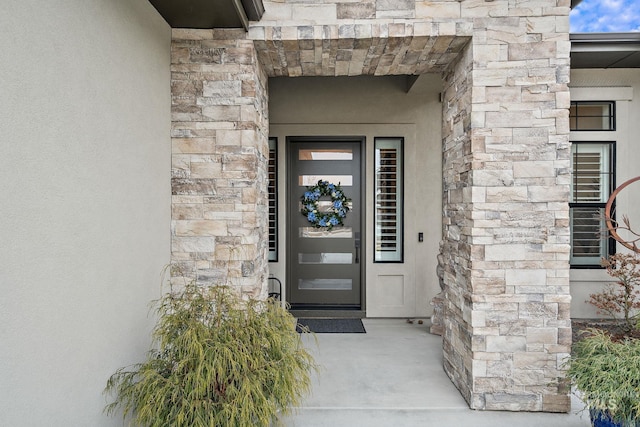 doorway to property with stone siding and stucco siding