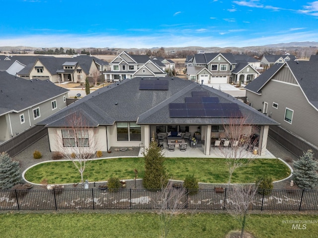 rear view of property with a patio, solar panels, a fenced backyard, and a residential view