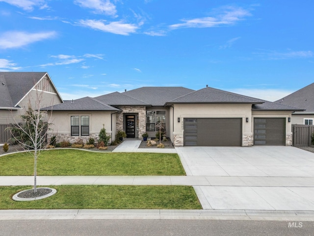 prairie-style house with an attached garage, stone siding, driveway, stucco siding, and a front yard