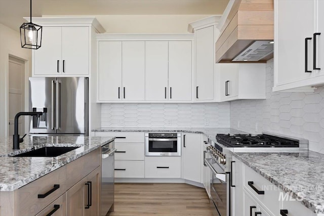 4069N 2200 2200 E E, Filer, ID 83328 - kitchen with premium appliances, a sink, custom range hood, hanging light fixtures, and light wood-style floors