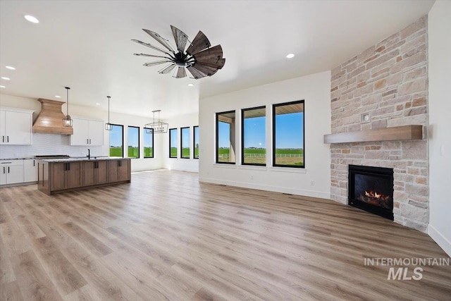 4069N 2200 2200 E E, Filer, ID 83328 - unfurnished living room with a sink, a stone fireplace, light wood-style floors, recessed lighting, and baseboards