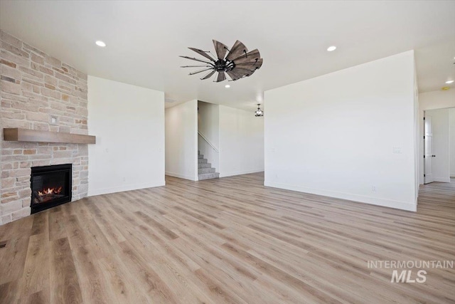 4069N 2200 2200 E E, Filer, ID 83328 - unfurnished living room with stairs, wood finished floors, a stone fireplace, baseboards, and recessed lighting