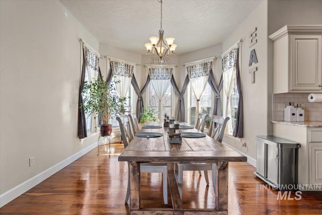 dining space featuring dark hardwood / wood-style floors, a textured ceiling, and an inviting chandelier