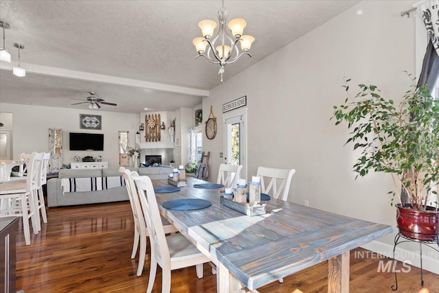 dining space featuring dark wood-type flooring, ceiling fan with notable chandelier, and a textured ceiling