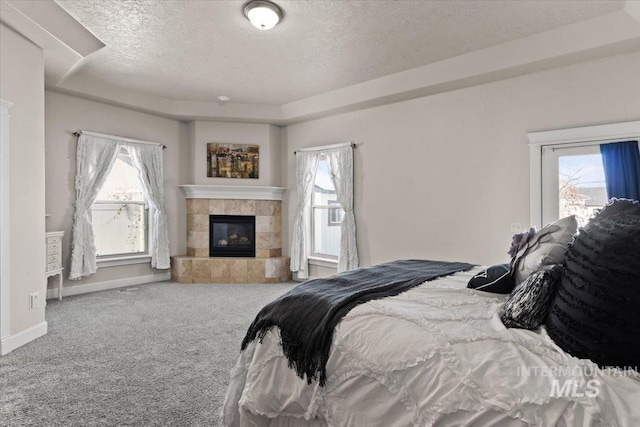 carpeted bedroom with multiple windows, a raised ceiling, and a textured ceiling