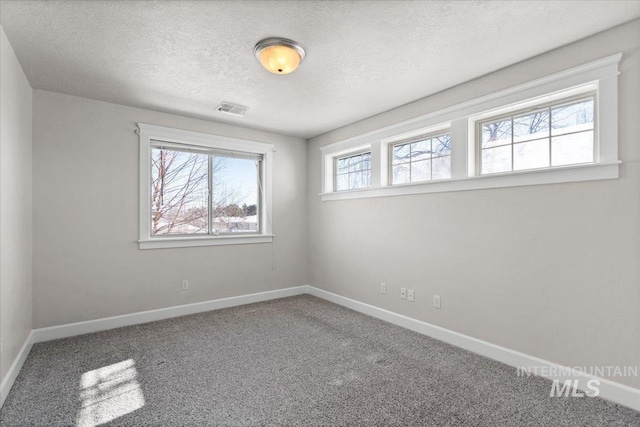 carpeted empty room with a textured ceiling