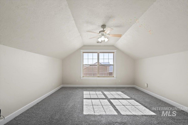 bonus room featuring ceiling fan, dark carpet, vaulted ceiling, and a textured ceiling