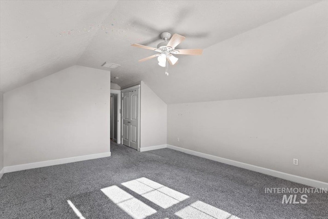 bonus room featuring ceiling fan, lofted ceiling, dark carpet, and a textured ceiling