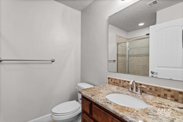 bathroom featuring vanity, toilet, a shower with door, and a textured ceiling