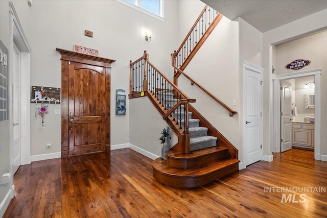 entrance foyer with a towering ceiling and dark hardwood / wood-style floors