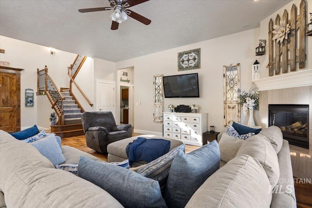 living room with ceiling fan, light hardwood / wood-style floors, and a textured ceiling