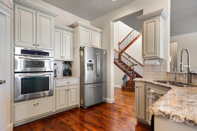 kitchen featuring dark hardwood / wood-style floors, tasteful backsplash, sink, light stone counters, and stainless steel appliances