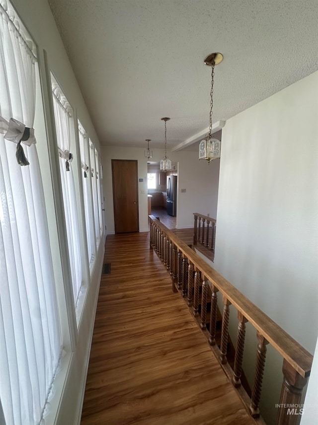 hallway with a notable chandelier, a textured ceiling, and dark hardwood / wood-style flooring