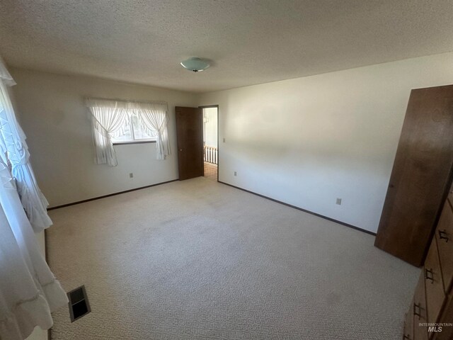 unfurnished bedroom with light carpet and a textured ceiling