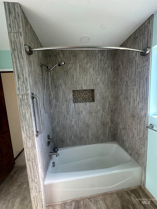 bathroom featuring a textured ceiling, tile patterned flooring, and tiled shower / bath