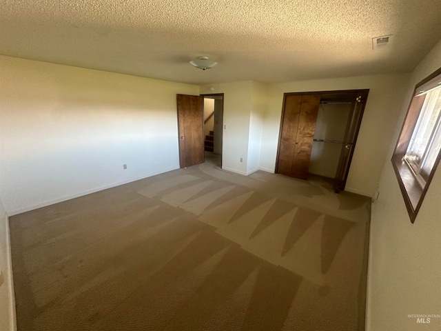 unfurnished bedroom with a textured ceiling and carpet floors