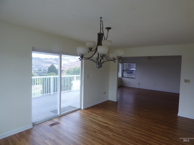 unfurnished dining area featuring a mountain view, a chandelier, and dark hardwood / wood-style floors