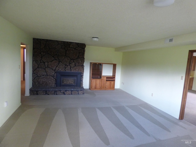 unfurnished living room with carpet, a fireplace, and a textured ceiling