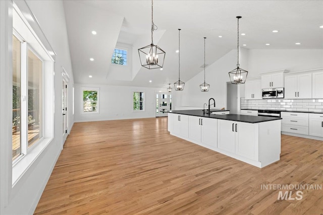 1006 Hill Rd, Homedale, ID 83628 - kitchen featuring high vaulted ceiling, stainless steel microwave, dark countertops, open floor plan, and white cabinets