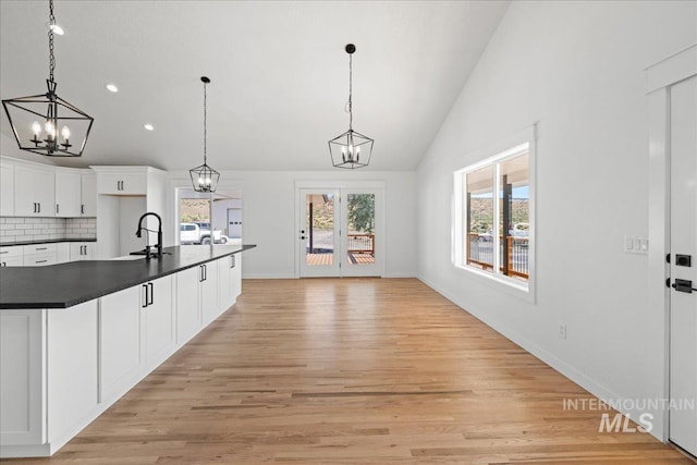 1006 Hill Rd, Homedale, ID 83628 - kitchen featuring a chandelier, dark countertops, lofted ceiling, backsplash, and white cabinetry