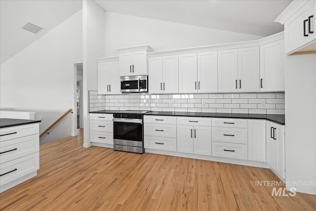 1006 Hill Rd, Homedale, ID 83628 - kitchen with stainless steel appliances, dark countertops, tasteful backsplash, white cabinets, and high vaulted ceiling
