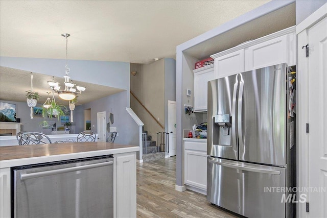 583 E Willowridge Ct, Kuna, ID 83634 - kitchen featuring stainless steel appliances, light wood-style flooring, a chandelier, white cabinetry, and decorative light fixtures