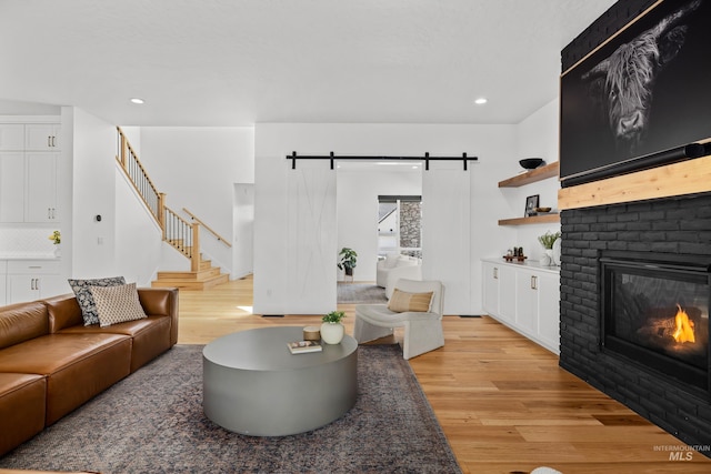 13684 N Sage Grouse Pl, Boise, ID 83714 - living room with stairs, light wood-type flooring, a barn door, recessed lighting, and a fireplace