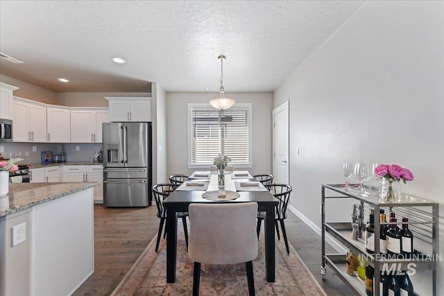 dining space with baseboards, recessed lighting, a textured ceiling, and wood finished floors