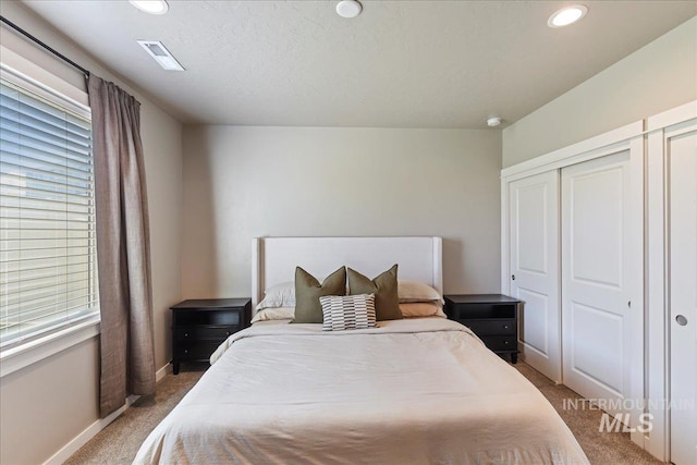 carpeted bedroom with recessed lighting, baseboards, visible vents, and multiple windows