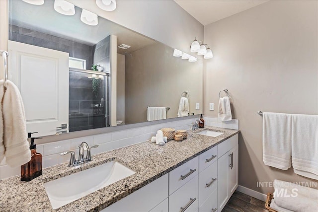 full bathroom featuring double vanity, a sink, baseboards, and a shower stall