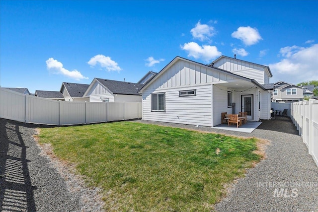 exterior space with board and batten siding, a lawn, a fenced backyard, and a patio area
