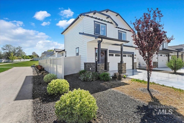 view of front facade featuring an attached garage, fence, stone siding, and concrete driveway