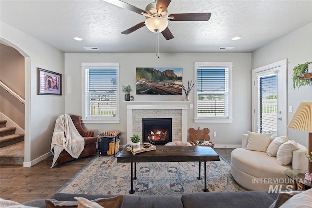 living area featuring baseboards, a textured ceiling, wood finished floors, and stairway