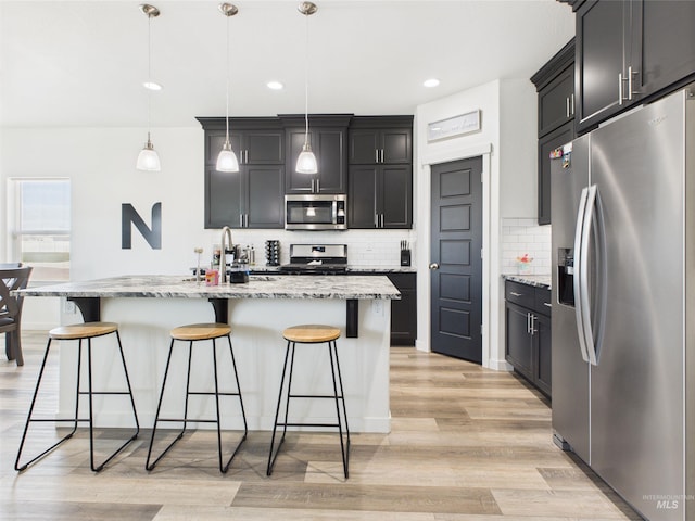 2420 Great Basin Way, Burley, ID 83318 - kitchen with stainless steel appliances, a kitchen bar, decorative backsplash, light wood-style floors, and light stone counters
