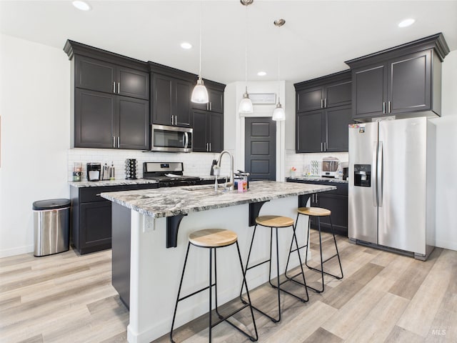 2420 Great Basin Way, Burley, ID 83318 - kitchen with appliances with stainless steel finishes, light stone countertops, a kitchen breakfast bar, light wood finished floors, and backsplash