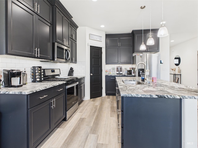 2420 Great Basin Way, Burley, ID 83318 - kitchen with stainless steel appliances, a sink, a kitchen island with sink, tasteful backsplash, and light wood-type flooring