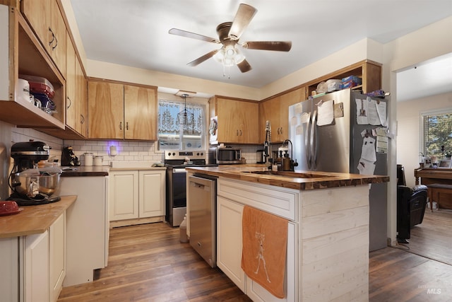 kitchen featuring appliances with stainless steel finishes, butcher block countertops, backsplash, wood-type flooring, and ceiling fan