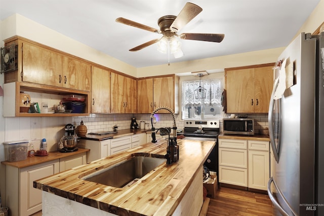 kitchen featuring wood counters, hanging light fixtures, ceiling fan, dark wood-type flooring, and appliances with stainless steel finishes