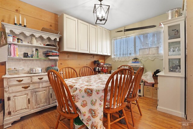 dining area with a chandelier, light hardwood / wood-style flooring, and lofted ceiling