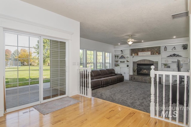 unfurnished living room with a textured ceiling, wood finished floors, visible vents, and built in features