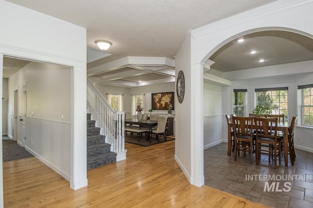 dining space with baseboards, arched walkways, stairway, ornamental molding, and wood finished floors