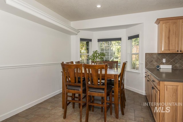 dining area with a textured ceiling, recessed lighting, stone tile flooring, and baseboards