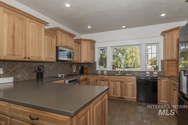 kitchen with dark countertops, decorative backsplash, stone finish flooring, a sink, and black appliances