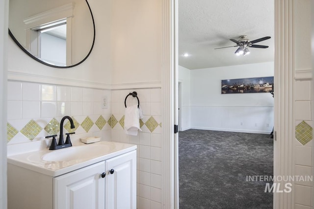 bathroom with a wainscoted wall, a ceiling fan, a textured ceiling, and vanity