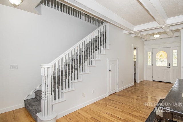 foyer featuring stairs, wood finished floors, beam ceiling, and baseboards