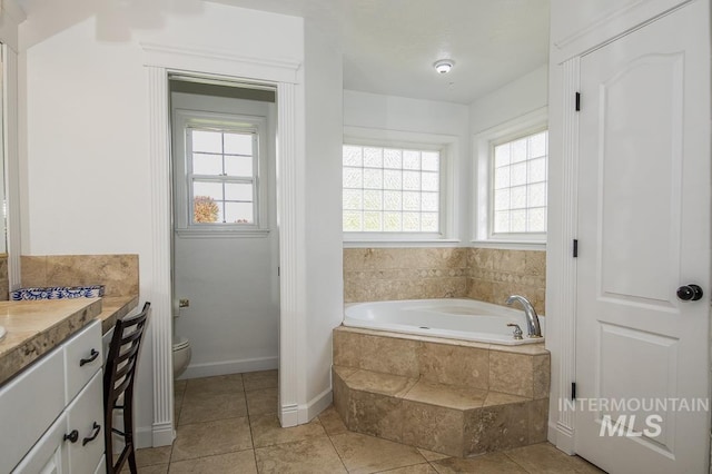 full bathroom with baseboards, toilet, tile patterned flooring, vanity, and a bath