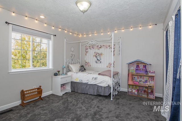 bedroom with a textured ceiling, dark colored carpet, visible vents, and baseboards