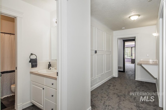 full bathroom featuring visible vents, toilet, vanity, a textured ceiling, and baseboards