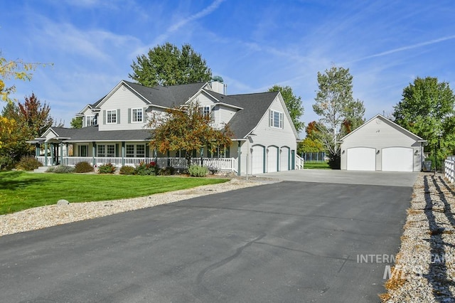 new england style home featuring a garage, a porch, a front yard, and aphalt driveway