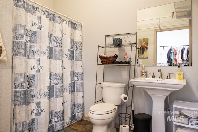 full bath with stone finish floor, toilet, and a shower with curtain